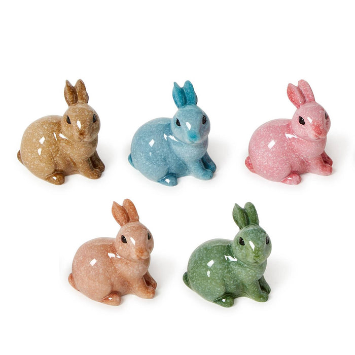 Five resin sitting rabbit figurines in different colors on a white background.