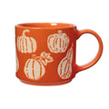 An orange ceramic mug with a handle, decorated with a wax relief design of cream-colored pumpkins and gourds, handle on the right, shown against a plain white background.