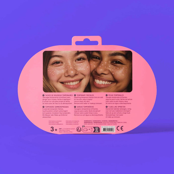 Back of freckle tattoo product packaging with a pink oval design featuring two smiling faces on a purple background.