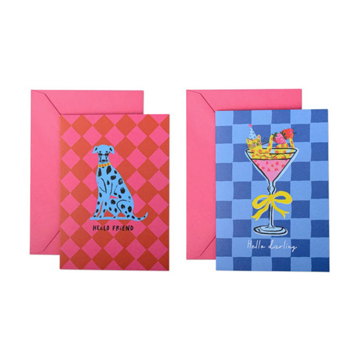 Two greeting cards with matching pink envelopes on a white background. The left card has a pink and red argyle pattern with a blue spotted dog illustration and the words 'Hello friend'. The right card has a blue checkerboard pattern with a cat in a cosmo glass illustration and the words "Hello darling."