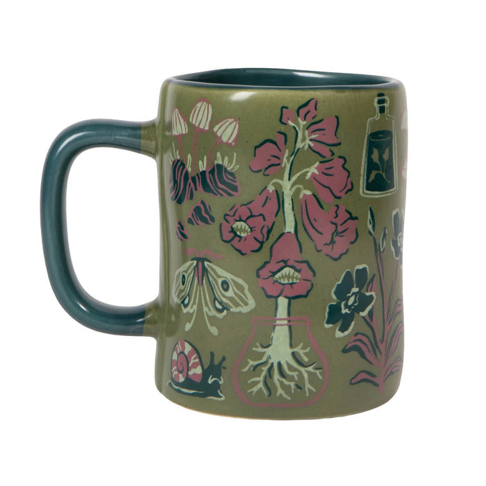 An olive green ceramic mug decorated with botanical and insect illustrations in pink, teal, and cream, shown on a plain white background.