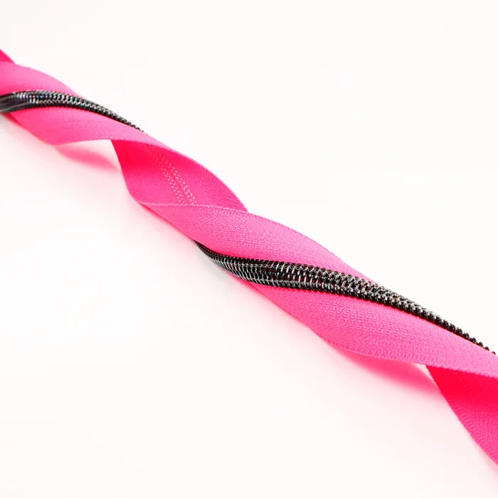 A very bright and fluorescent hot pink zipper tape with midnight rainbow coil teeth. This photo is of the zipper tape twirled.