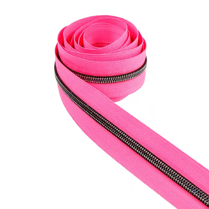 A very bright and fluorescent hot pink zipper tape with midnight rainbow coil teeth. This photo is of the zipper tape rolled up.