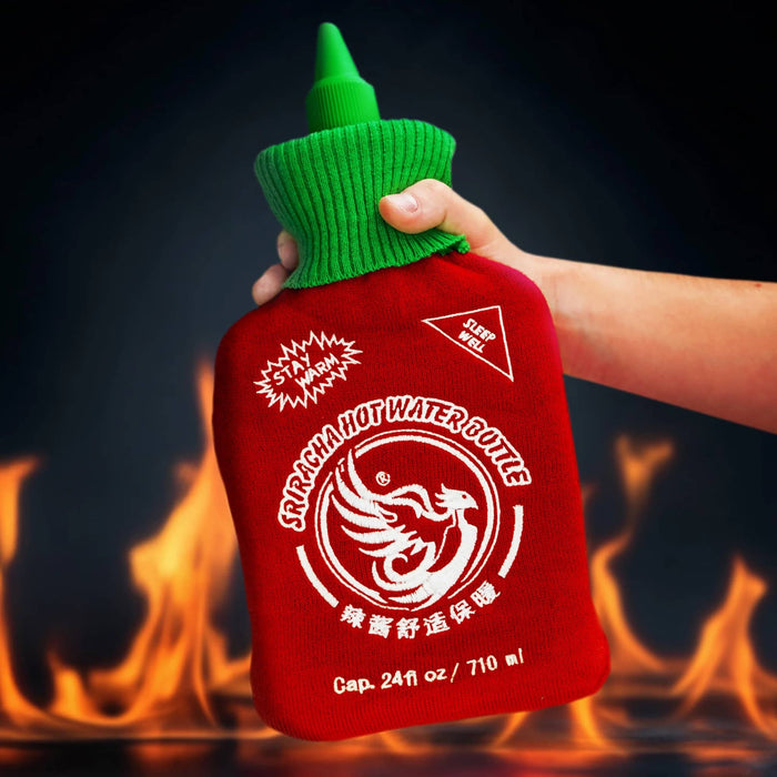 Red hot water bottle with green lid held by a hand against a dark background with flames.