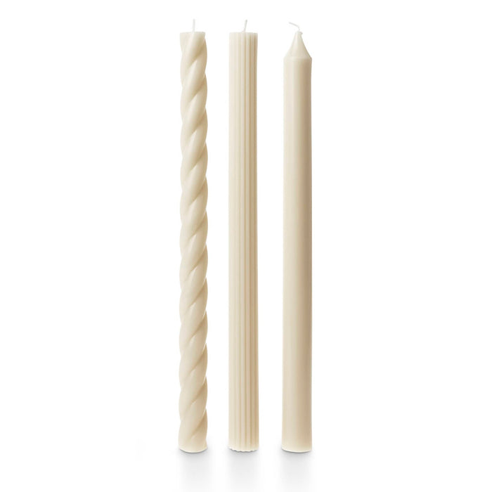 A set of 3 tall cream taper candles in different textures, a twisted spiral, a ribbed and a smooth, standing upright on a white background.