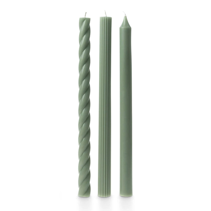 A set of 3 tall sage green taper candles in different textures, a twisted spiral, a ribbed and a smooth, standing upright on a white background.