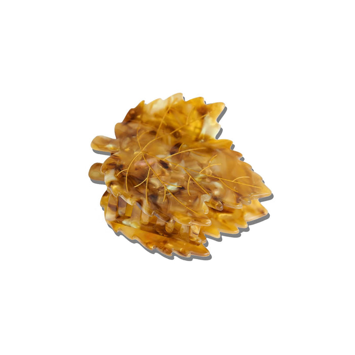 A Japanese maple leaf shaped hair claw clip with an iridescent amber finish and gold vein-like lines, side and front view with a soft gray shadow, centered on a plain white background.