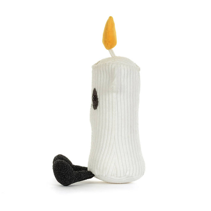 A white corduroy ghost candle plush toy with a yellow-orange flame on top, black embroidered eyes and mouth, and black feet, side view, shown on a plain white background.
