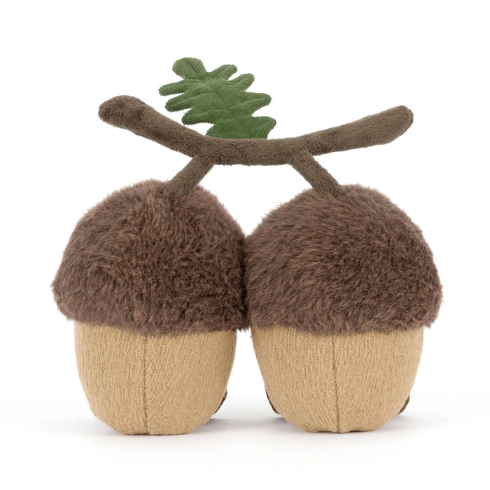 Two plush acorns with faces connected with a velvet branch, back view, on a white background.
