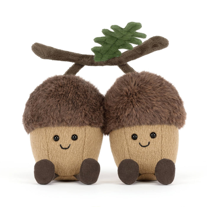 Two plush acorns with faces connected with a velvet branch, front view, on a white background.