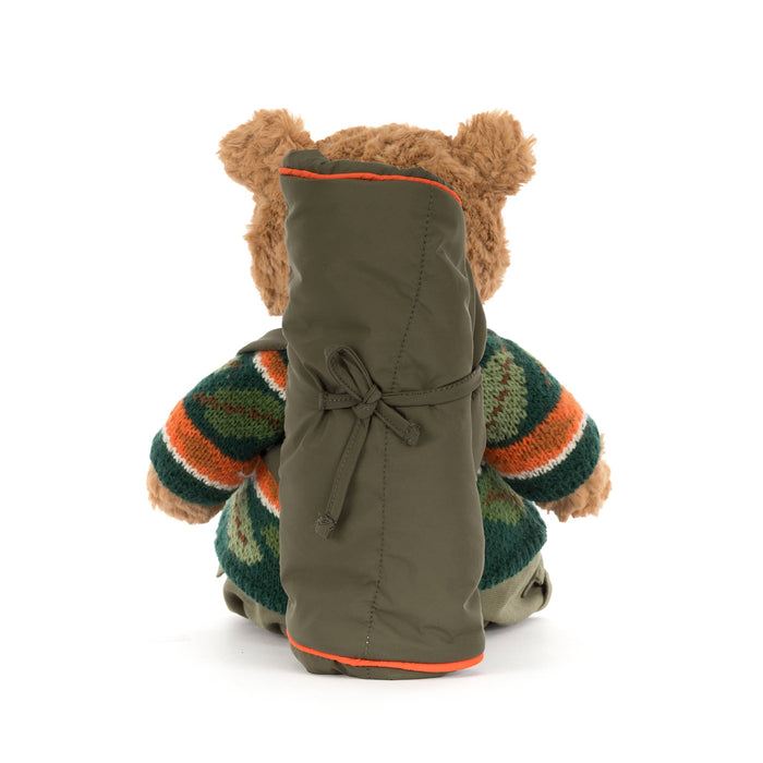 Jellycat Bartholomew Bear plush with a knit sweater in fall colors and a sleeping bag backpack, back view, on a white background.