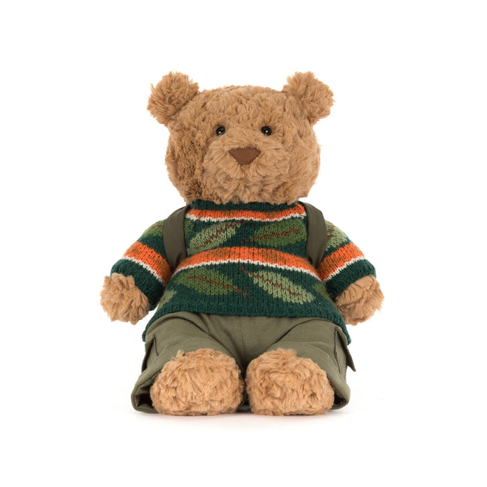 Jellycat Bartholomew Bear plush with a knit sweater in fall colors and a sleeping bag backpack, front view, on a white background.