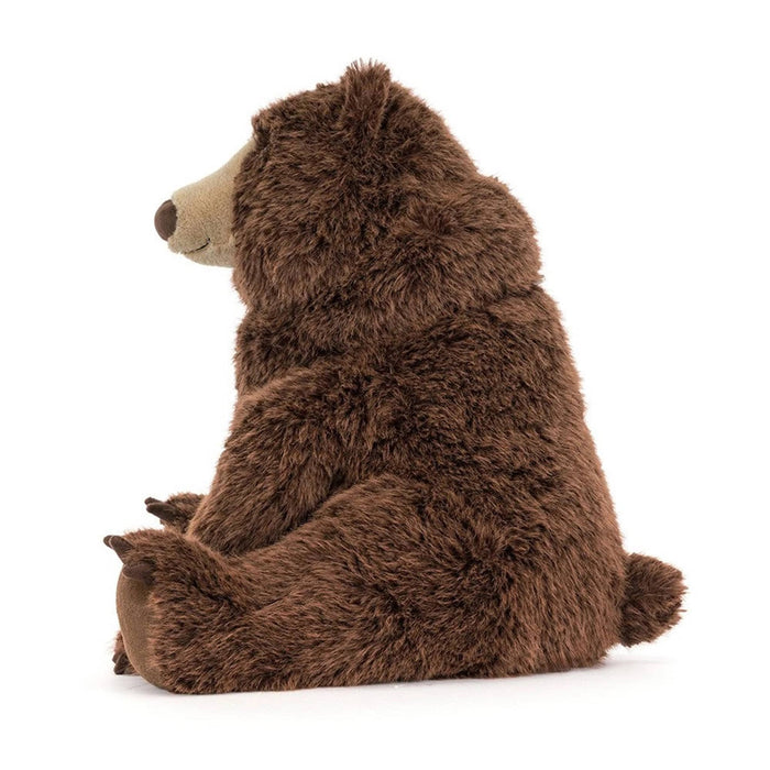 A brown plush stuffed bear toy sitting upright, side view on a clean white background.