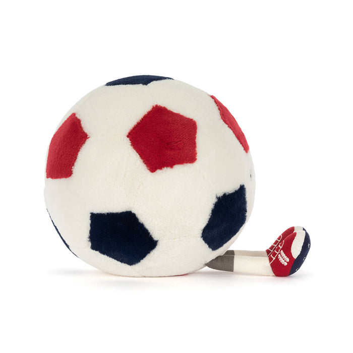 Plush toy soccer ball in red, white, and blue with smiling face, side view, sitting on a white background.