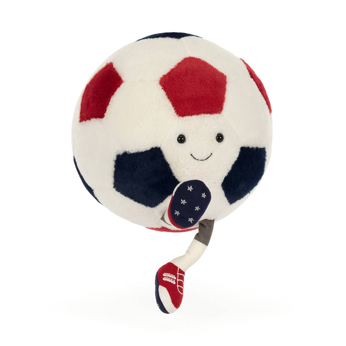 Plush toy soccer ball in red, white, and blue with smiling face, front angle view, kicking on a white background.