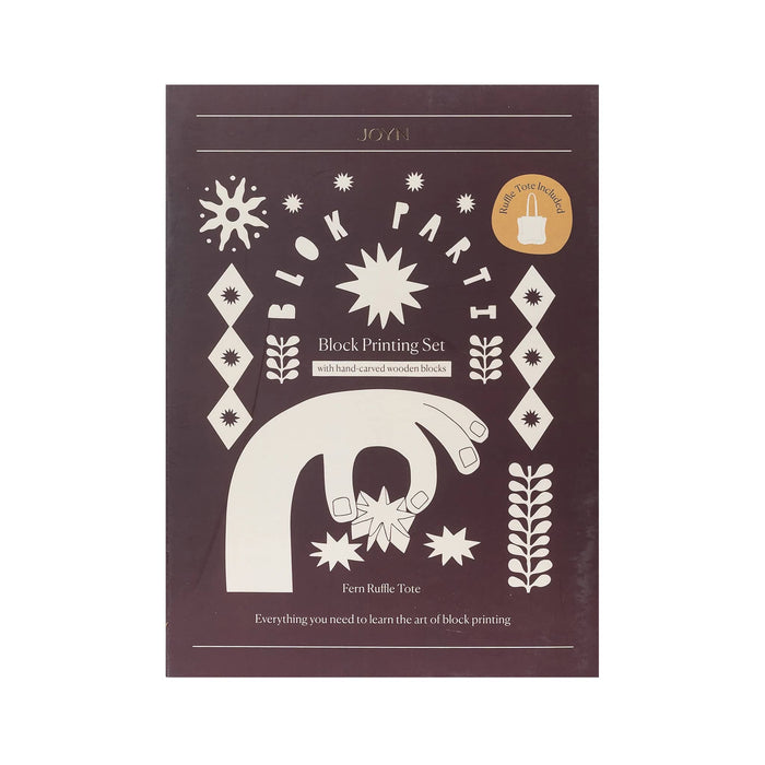 Front of JOYN Blok Parti Fern Ruffle Tote Block Printing Set, featuring a dark mahogany background with cream-colored block printing illustrations of hands, stars, and geometric patterns, on a plain white background.