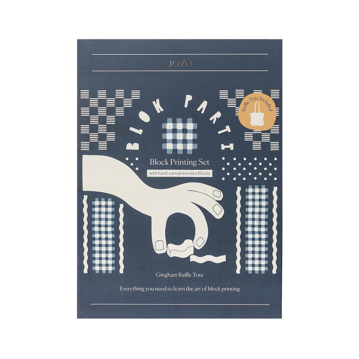 Front of JOYN Blok Parti Gingham Ruffle Tote Block Printing Set, featuring a dark blue background with cream-colored block printing illustrations of hands, dots, and square patterns, on a plain white background.