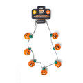 A Halloween-themed jumbo flashing pumpkin necklace on a black cord, featuring multiple orange glitter pumpkins with black jack-o'-lantern faces and green accents, attached to a black retail header card.