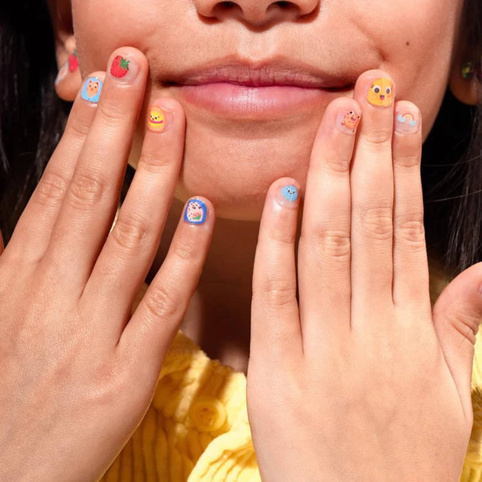 Close-up of a person with colorful nail stickers holding their hands near their face.