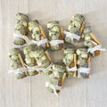 Smudge bundles with dried white roses, palo santo and an agate crystal, tied with white fabric ribbons on a textured off-white background.