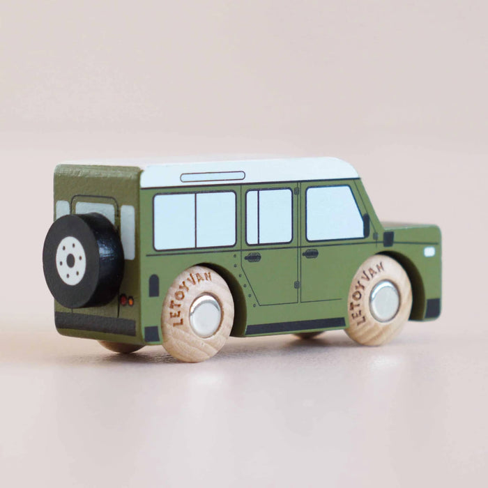 Green toy SUV with wooden wheels, back angle view, on a beige background.