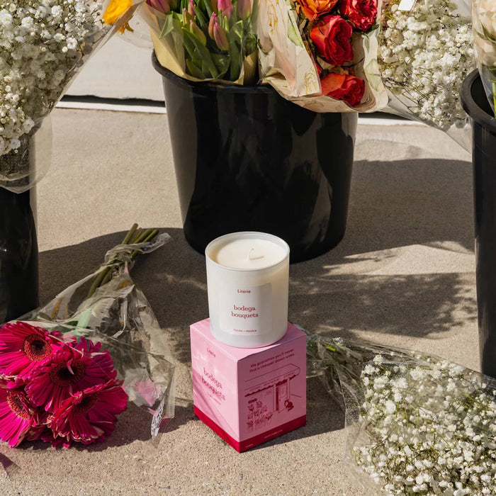 Candle on a pink box with flowers around it.