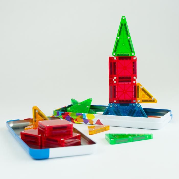 Magna-Tiles microMAGS 26 piece travel set with rocket ship started using the tin packaging as a base, on a white background.