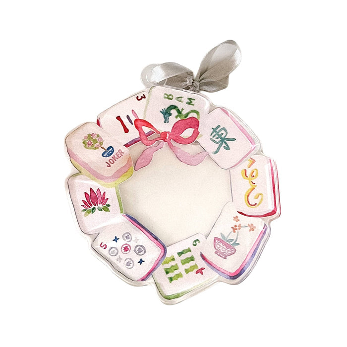 An acrylic ornament featuring illustrated mahjong tiles arranged as a wreath with a silver hanging ribbon at the top, shown on a plain white background.