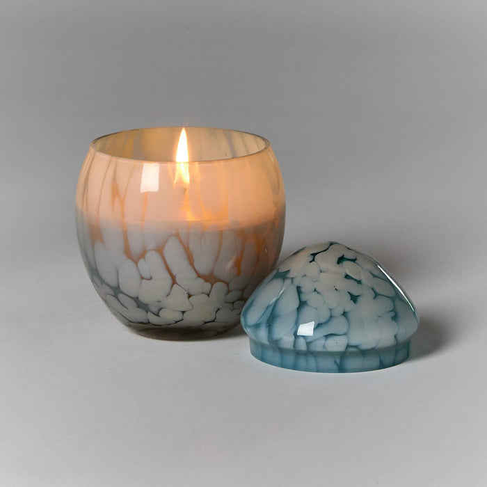 Blue glass egg-shaped candle holder with a lit candle on a gray background.