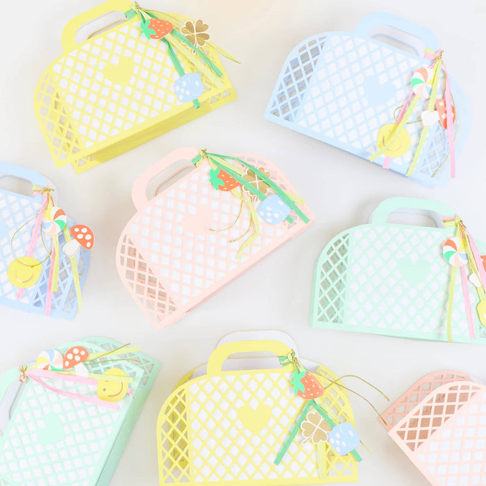 Colorful pastel mesh favor bags with handles and decorative elements on a white background.