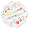 Decorative paper plate with colorful letters and charms on a white background.