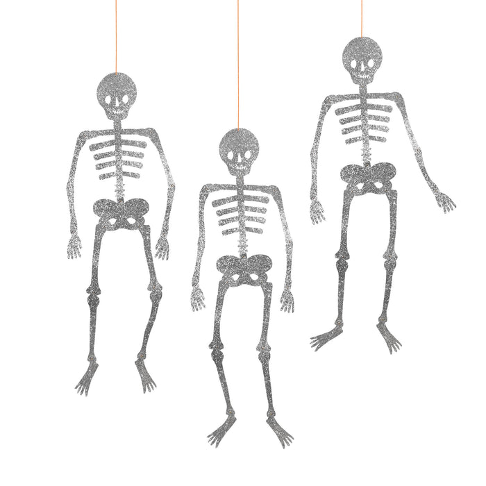 Three giant glittery skeleton figures hanging against a white background.