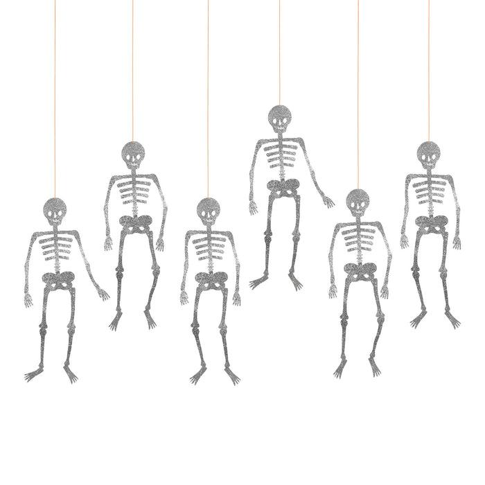 Six silver glitter hanging skeleton decorations suspended by thin orange strings on a plain white background.