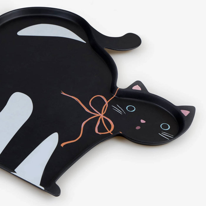 Detail of a black cat-shaped serving tray with an orange bow on a white background.