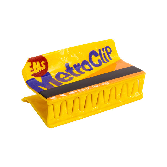 A bright yellow hair claw clip with blue 'MetroClip' branding and a black magnetic strip, shown on a plain white background.
