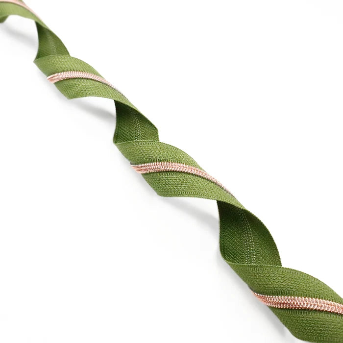 Muted shade of green zipper tape with rose gold coil teeth. This photo is of the zipper tape twirled.