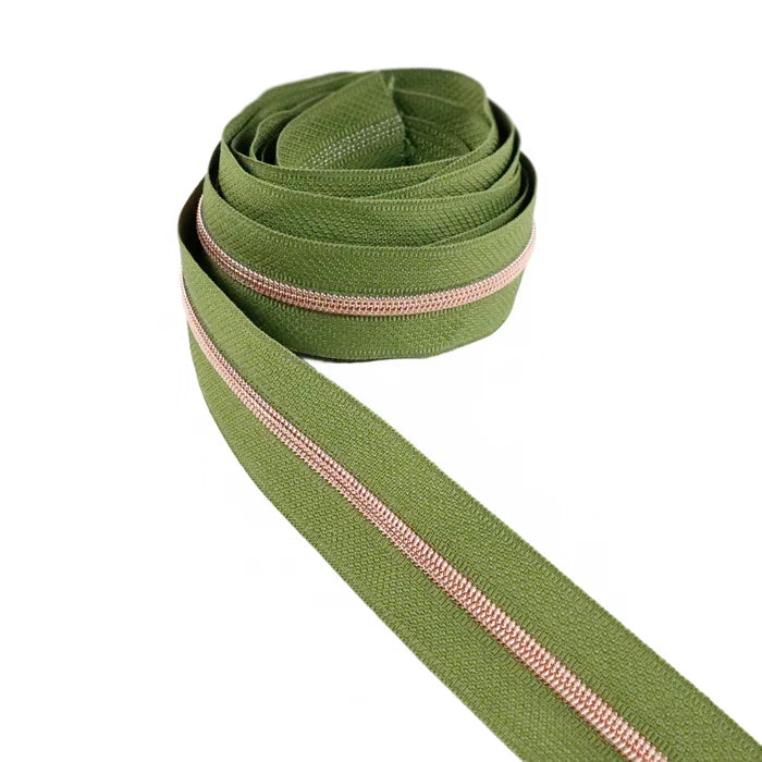 Muted shade of green zipper tape with rose gold coil teeth. This photo is of the zipper taped rolled up.