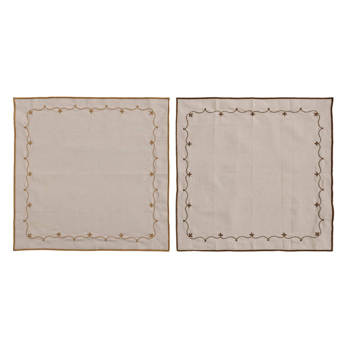 Two square beige cotton napkins with embroidered borders, displayed side-by-side on a white background.