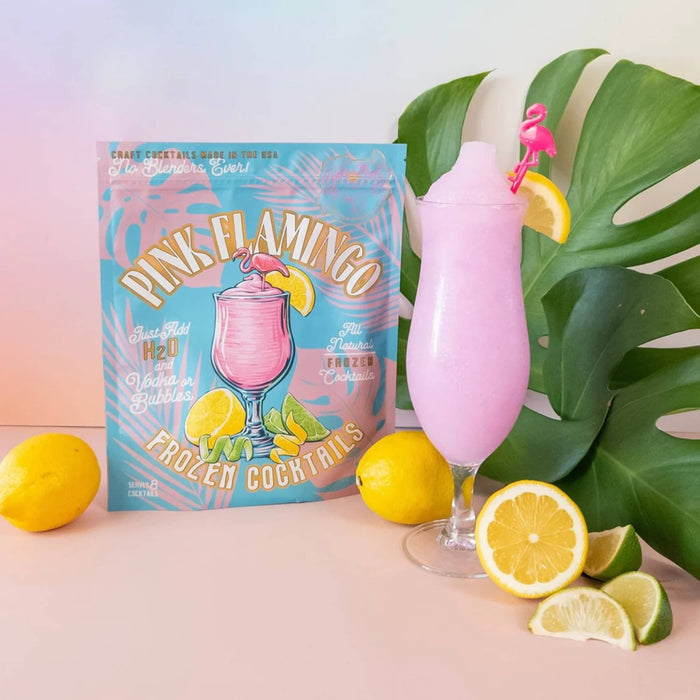 Pink flamingo-themed frozen cocktail kit with a pink drink in a glass, lemons, and limes on a pastel background.