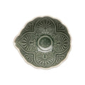 A top-down view of a ceramic bowl with a scalloped edge and embossed floral patterns, featuring a muted sage green glaze and a contrasting warm cream rim, set against a plain white background.
