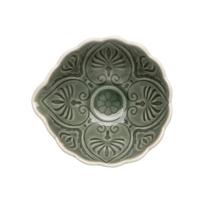 A top-down view of a ceramic bowl with a scalloped edge and embossed floral patterns, featuring a muted sage green glaze and a contrasting warm cream rim, set against a plain white background.