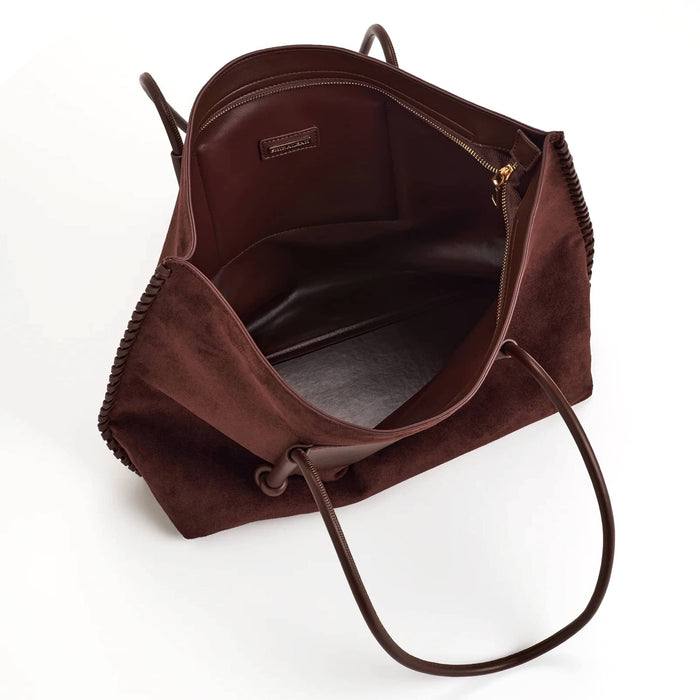 A dark brown vegan suede tote bag shown open from an overhead angle, displaying its interior space, zipper, and handles against a clean white background.