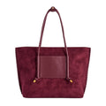 A deep red vegan suede tote bag with a smooth vegan leather front pocket and matching shoulder straps, finished with small gold-tone hardware, front view shown against a plain white background.