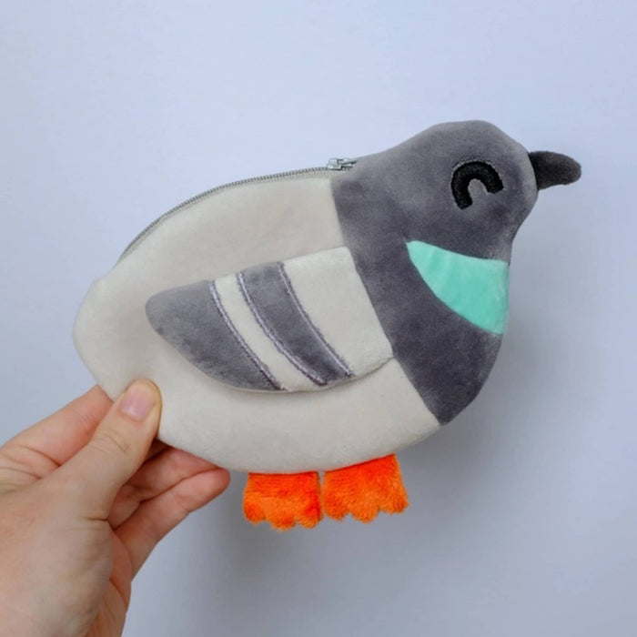 Plush pigeon-shaped coin purse held by a hand against a light gray background.