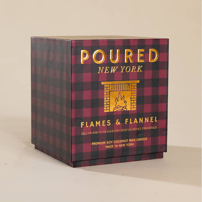 A square product box for a candle, featuring a black and dark red buffalo plaid pattern with gold foil lettering that reads 'POURED NEW YORK' and 'FLAMES & FLANNEL'. The box is photographed on a neutral beige background.