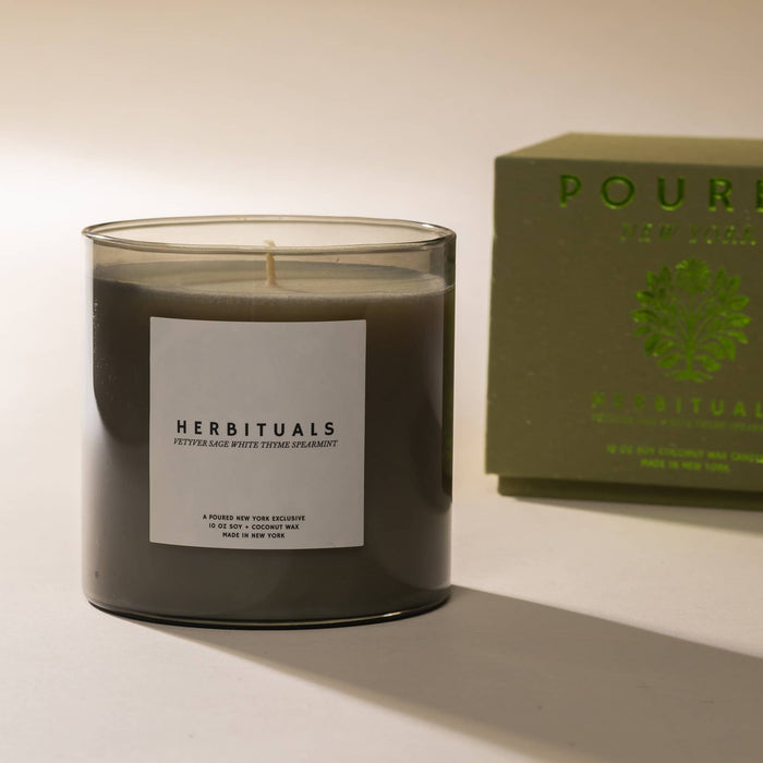 Herbituals candle with a label and a green box in the background on a light background.