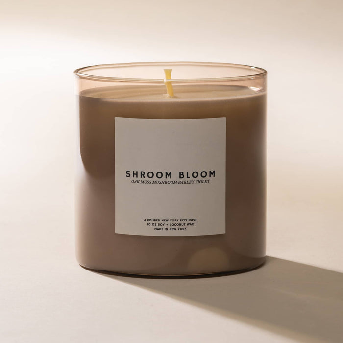 Candle with a label titled 'Shroom Bloom' on a white background.