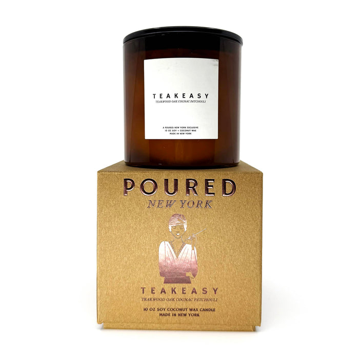 A Teakeasy scented candle in an amber glass jar with a black lid, displayed on top of its textured kraft cardboard packaging box. The brand 'POURED NEW YORK' and 'Teakeasy' is clearly visible on the box in foil.