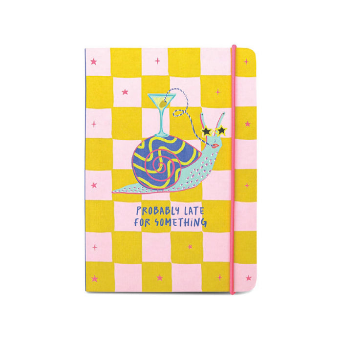 A softcover notebook with a pink and yellow checkerboard pattern, featuring a whimsical blue snail illustration with a cocktail glass on its shell and the text 'PROBABLY LATE FOR SOMETHING' on the front. It has a hot pink elastic closure band.