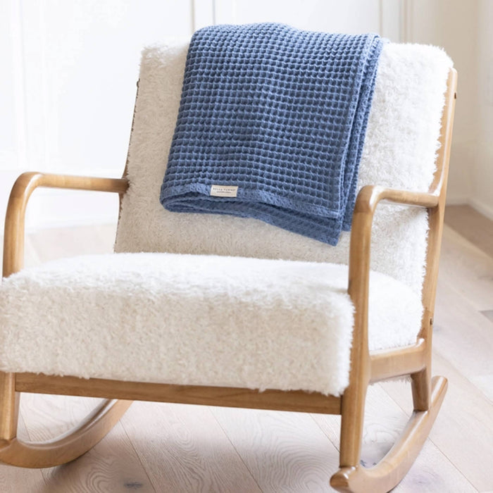 Bella Tunno Rain Cotton Waffle Weave Baby Blanket, folded and draped on white fluffy rocking chair.